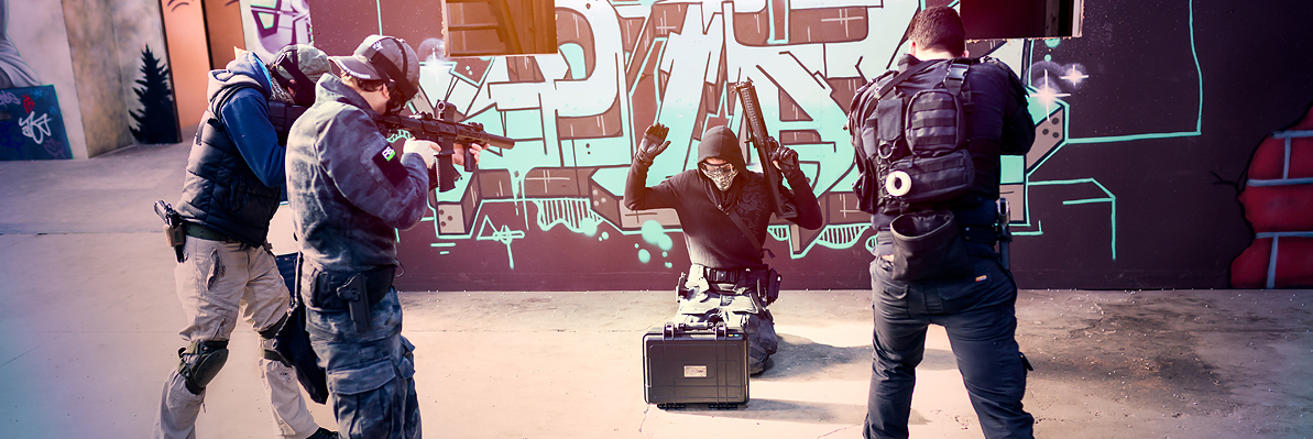 Airsoft players advancing on an IWG objective prop during a milsim game